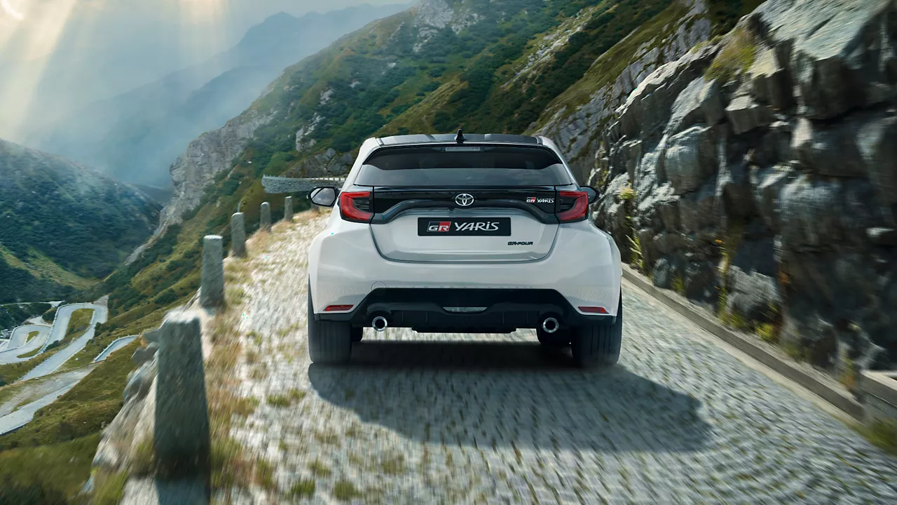 Toyota GR Yaris driving past a waterfall