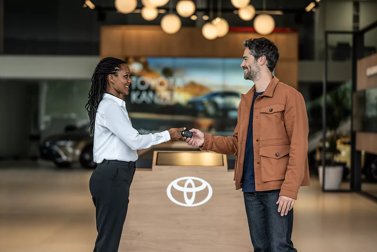 Consultant handing keys to customer at dealership