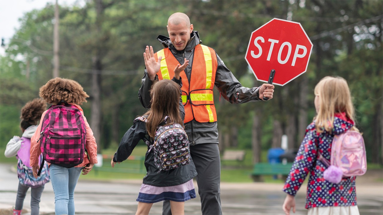 Community worker helping children cross the street